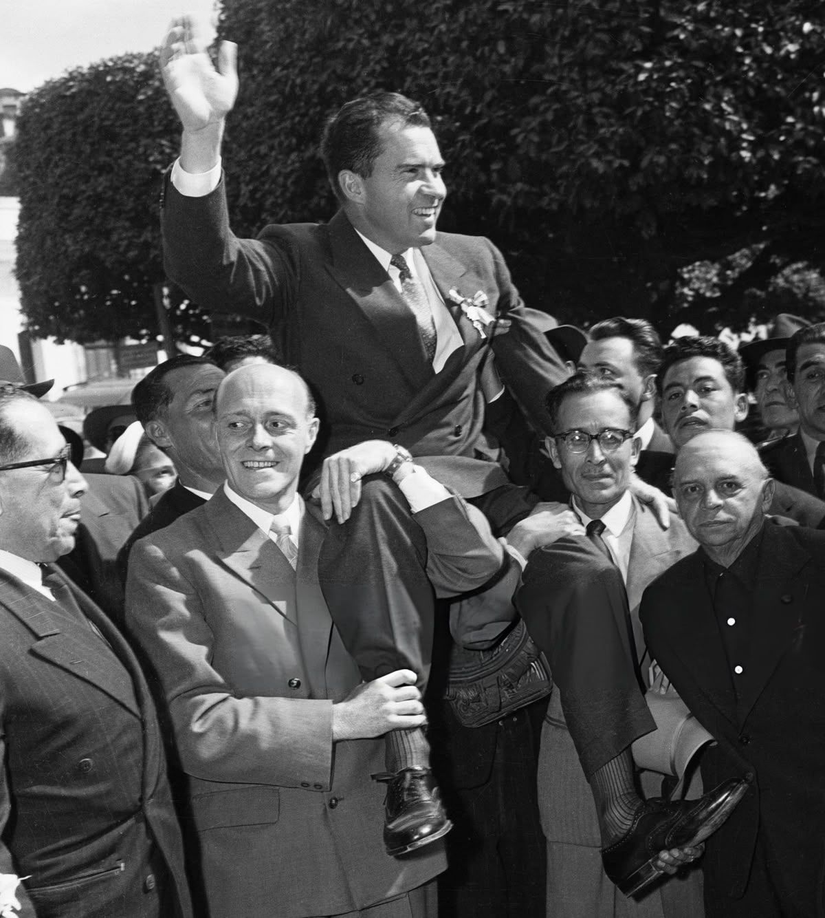 Richard Nixon waving while being carried through a crowd