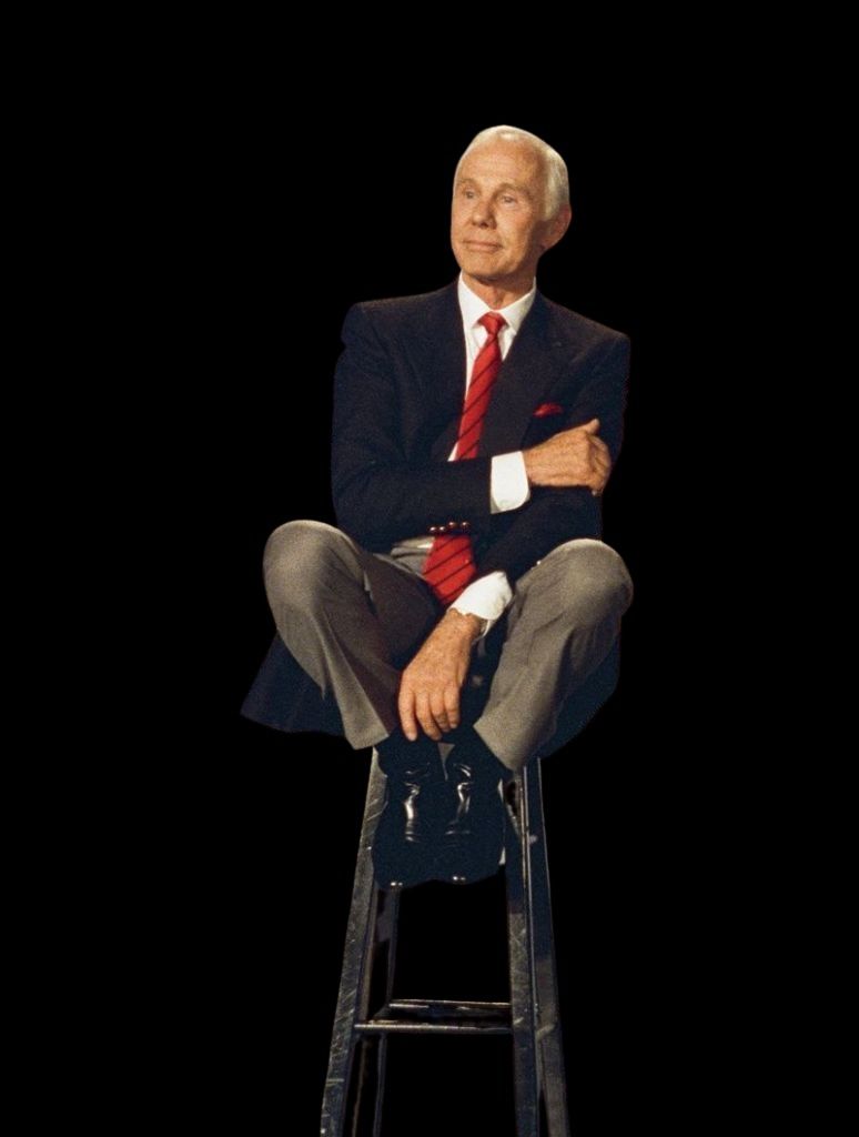 Johnny Carson seated on a stool