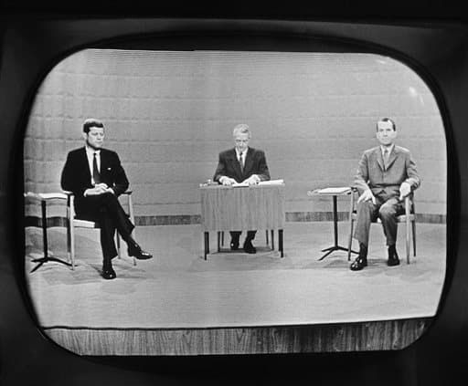 Black-and-white television image of candidates seated for a broadcast debate